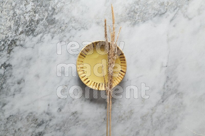 Wheat stalks on multicolored pottery plate on grey marble background