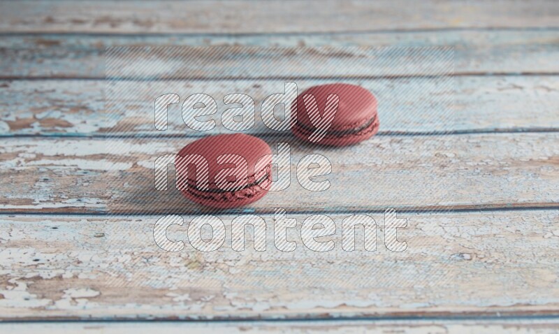 45º Shot of two Red Cherry macarons on light blue wooden background