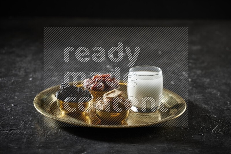 Dried fruits in metal bowls with sobya on a tray in dark setup