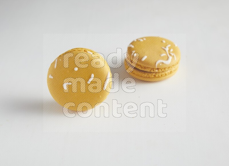 45º Shot of two Yellow Piña Colada macarons on white background