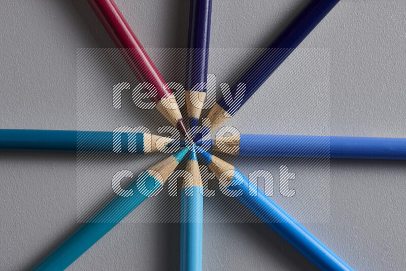 An arrangement of colored pencils in different colors on grey background
