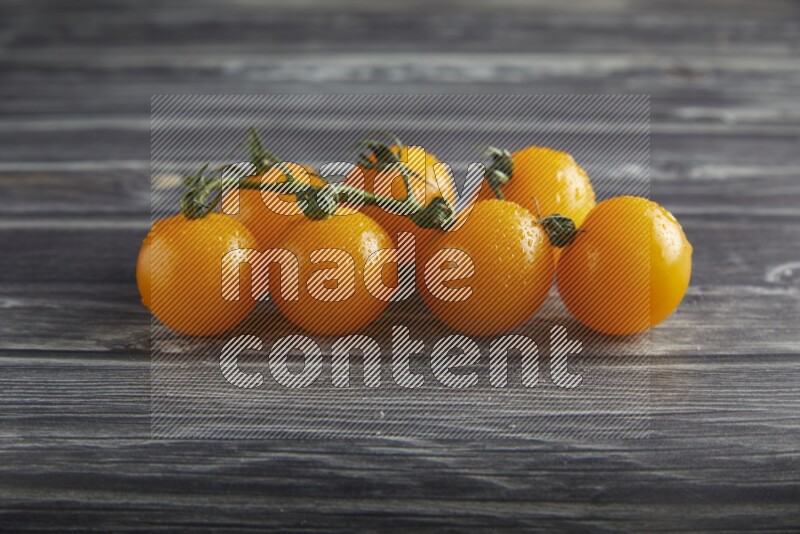 Yellow cherry tomato vein on a textured grey wooden background 45 degree