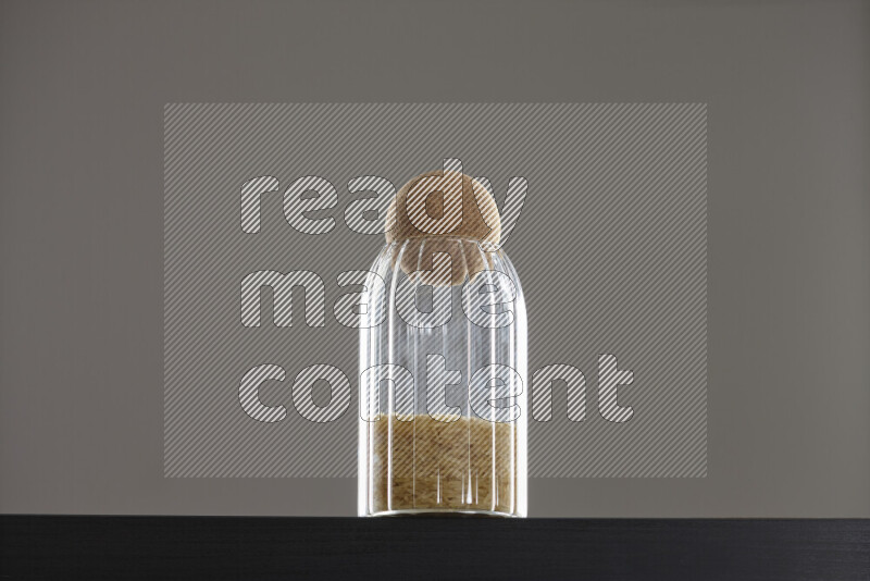 Basmati golden rice in a glass jar on black background