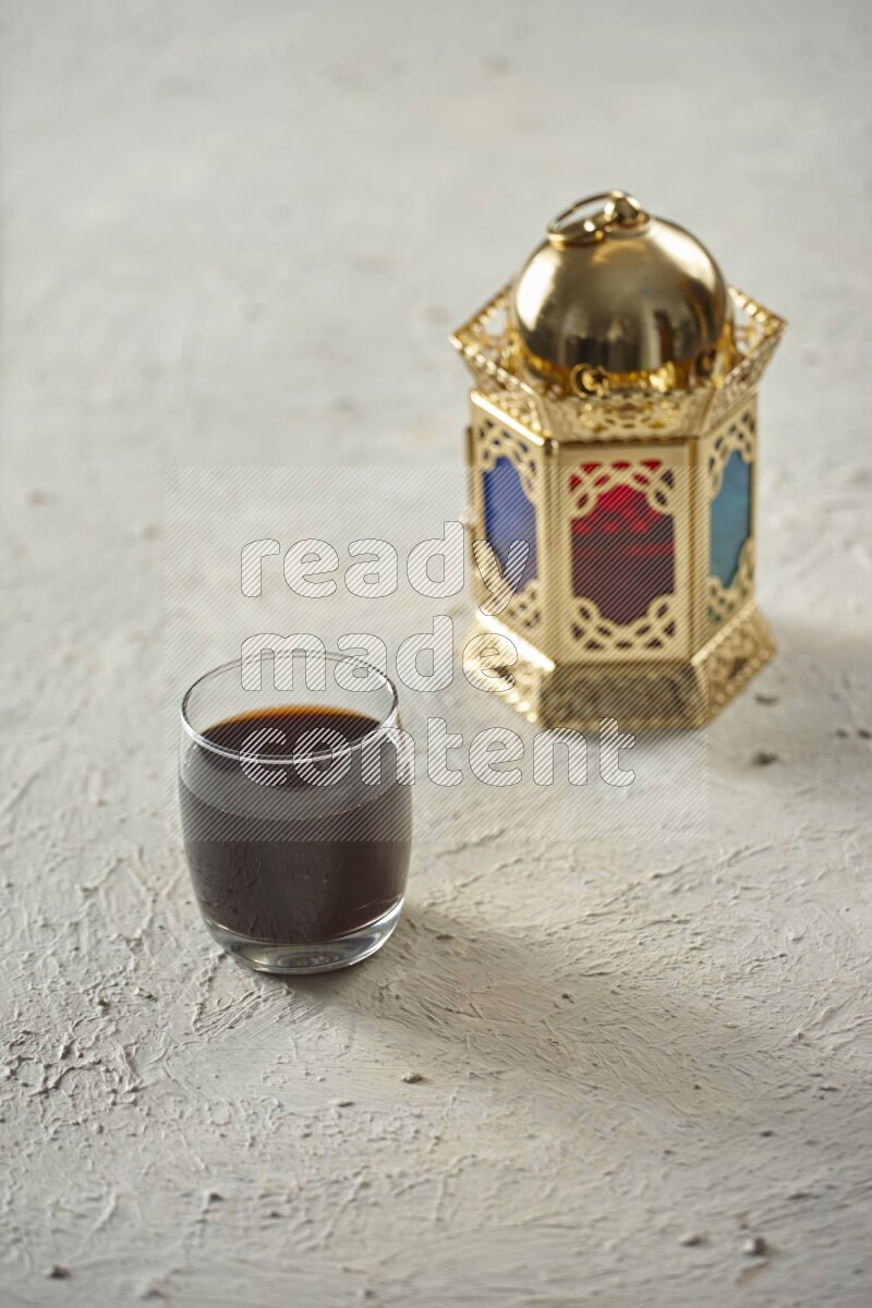 A golden lantern with different drinks, dates, nuts, prayer beads and quran on textured white background