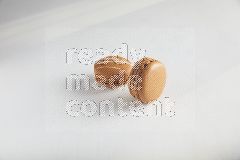 45º Shot of of two assorted Brown Irish Cream, and Brown Maple Taffy macarons  on white background
