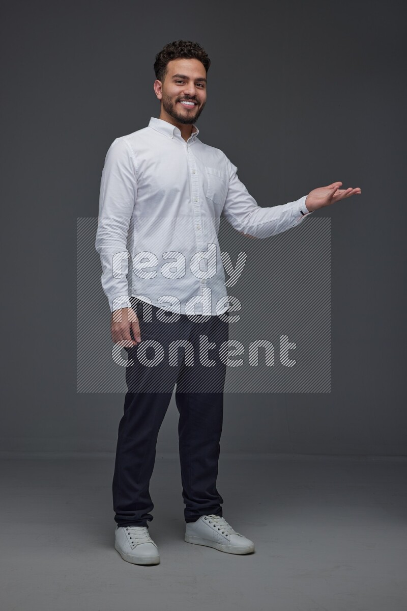 A man wearing smart casual standing and making multi hand gestures eye level on a gray background