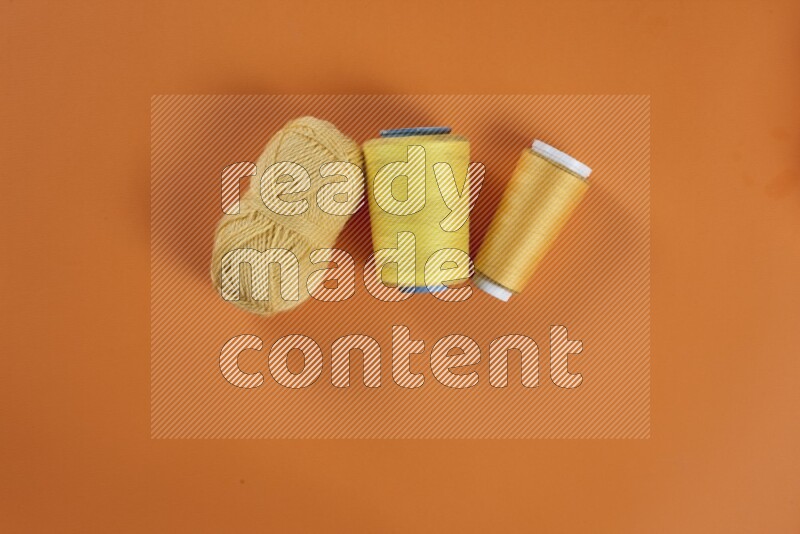 A yellow collection of sewing and tailoring tools arranged on a orange background