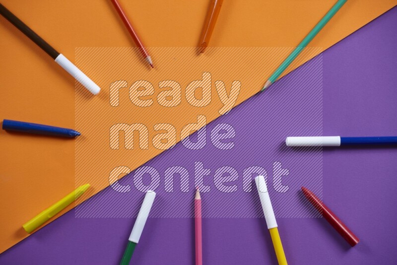 A mix of colored pencils, crayons on orange and purple background