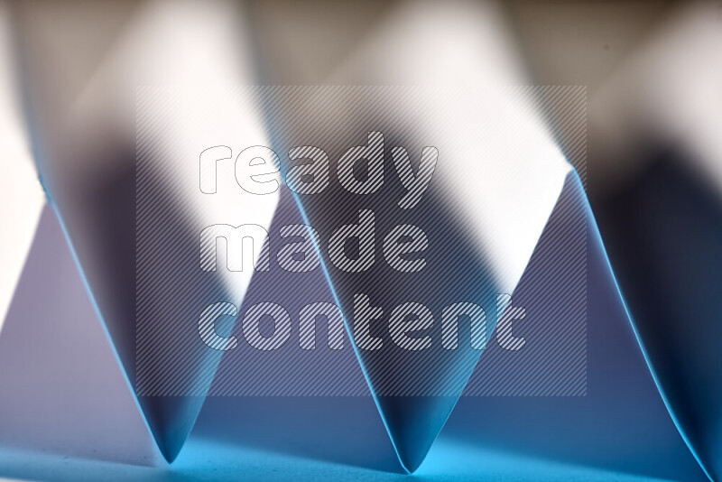 A close-up abstract image showing sharp geometric paper folds in white and blue gradients