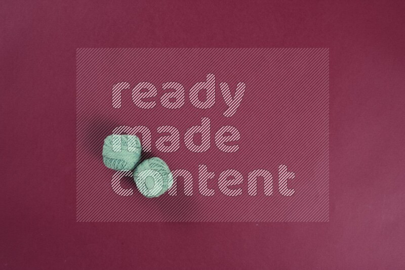 A green and red collection of sewing and tailoring tools arranged on a red background