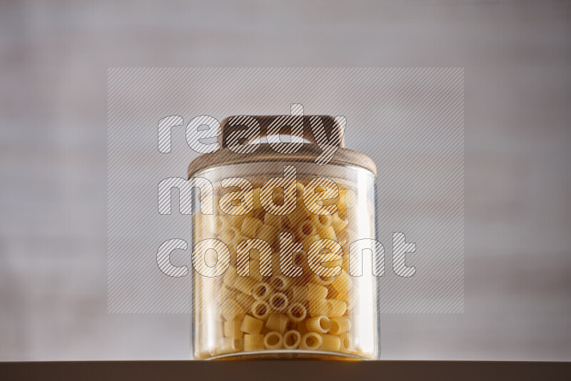 Raw pasta in glass jars on beige background