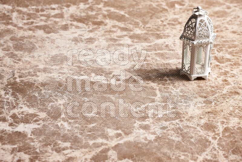 A candle lantern on beige marble background