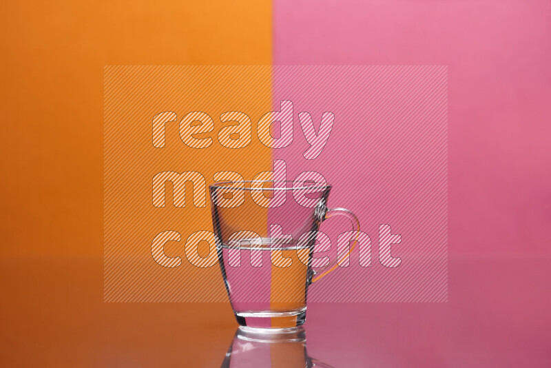 The image features a clear glassware filled with water, set against orange and pink background