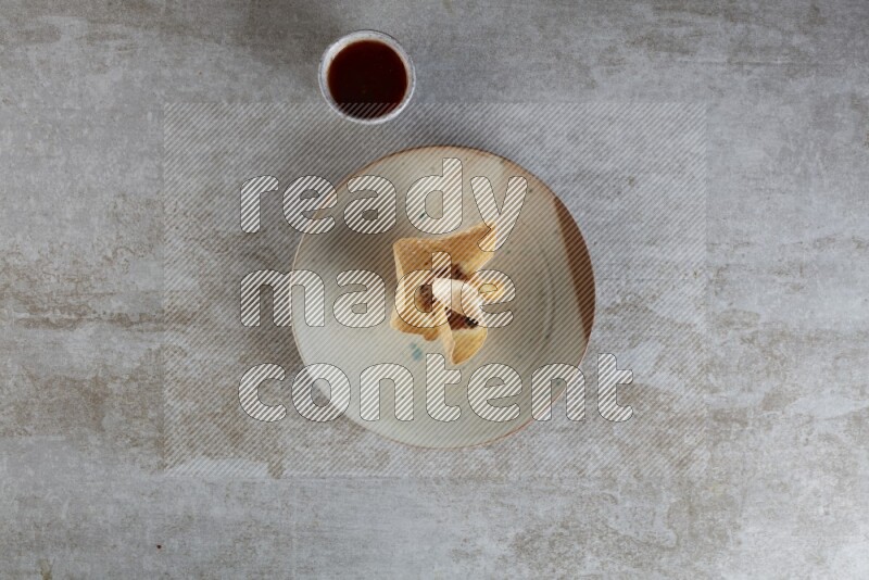 wonton cups with soy sauce ramkin on multi colored pottery on grey textured counter top