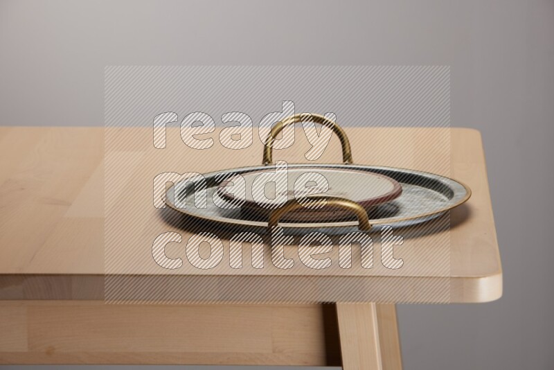 multicolored plate placed on a rounded stainless steel tray with golden handels on the edge of wooden table