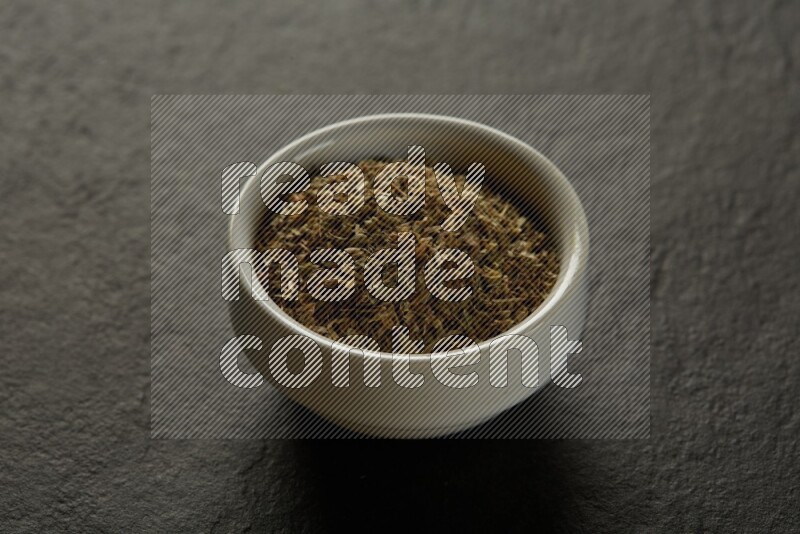 white ceramic round sauce bowl filled with herbs on grey textured countertop