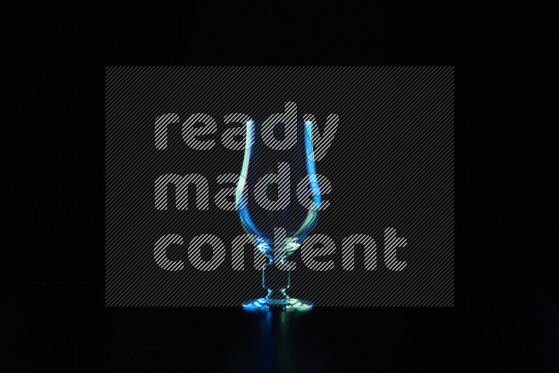 Glassware with rim light in blue and green against black background