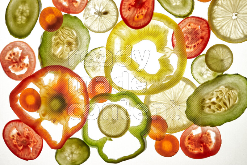 Mixed vegetables and fruits slices on illuminated white background