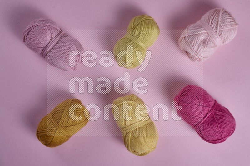 A yellow and pink collection of sewing and tailoring tools arranged on a pink background