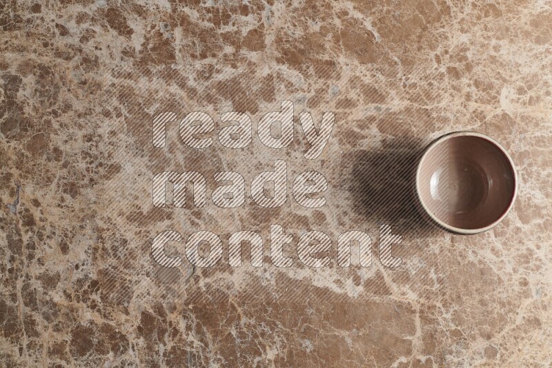 A multicolored pottery bowl on beige marble background