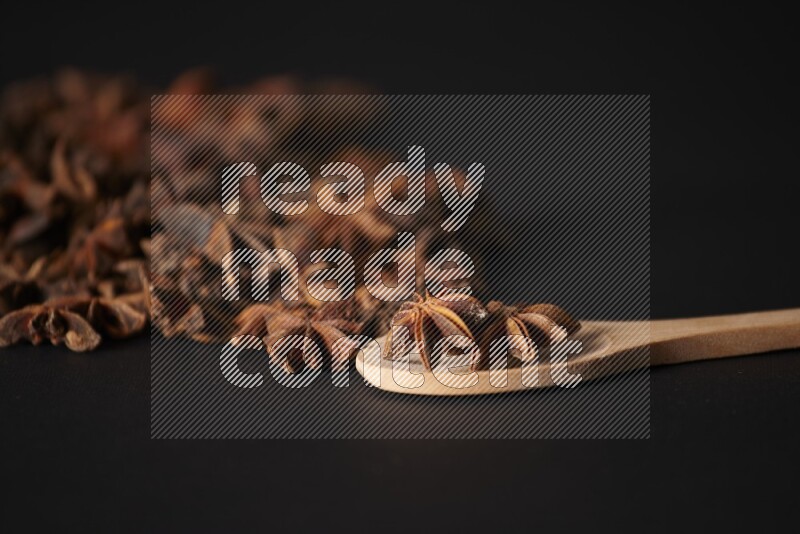 Star Anise in a wooden spoon and spreading on a black flooring