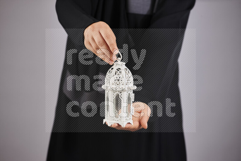 A woman in black abaya holding different ramadan lanterns in different positions