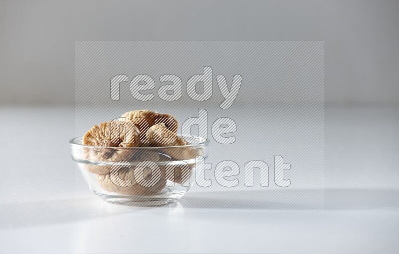 A glass bowl full of dried figs on a white background in different angles