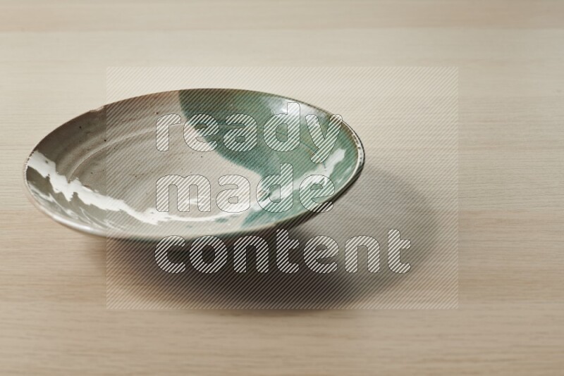 A multicolored pottery plate on light wooden background