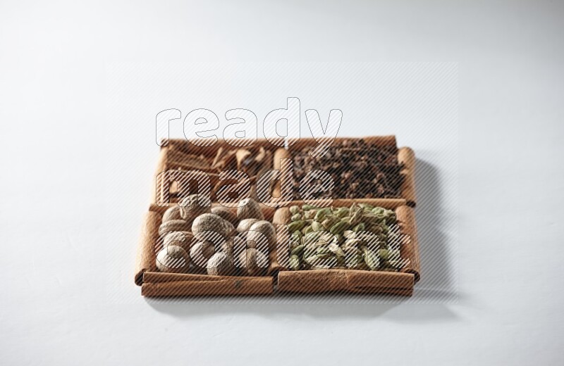 4 squares of cinnamon sticks full of cardamom, cinnamon, cloves and nutmeg on white flooring