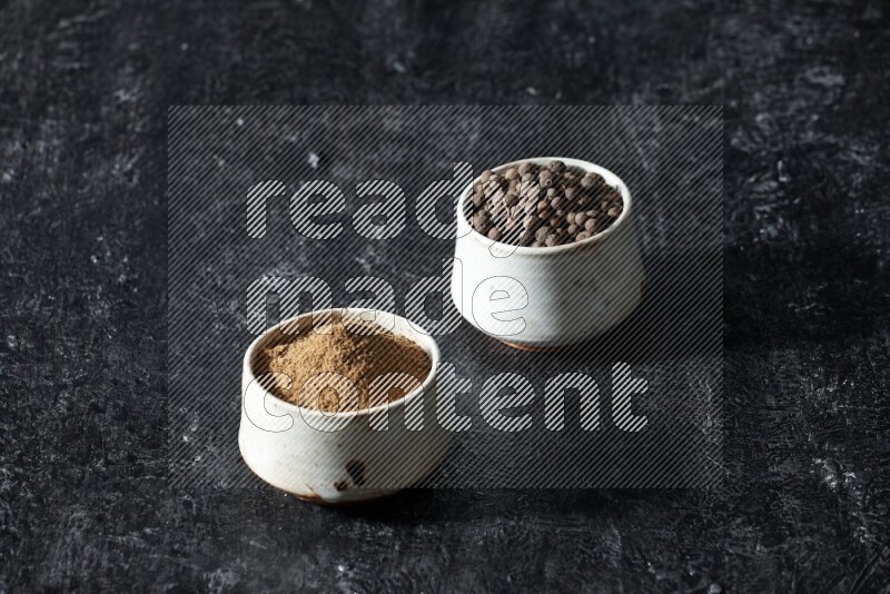 وعاءان بيج، أحدهما ممتلئ ببودرة بهار الفلفل الحلو والآخر بالحبوب على خلفية سوداء