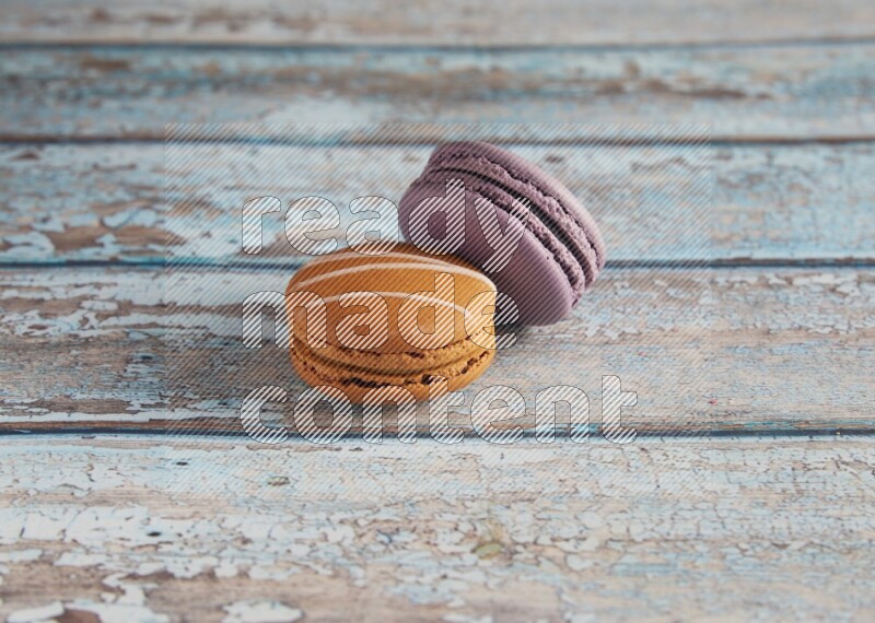 45º Shot of of two assorted Brown Irish Cream, and Purple Blueberry macarons  on light blue background