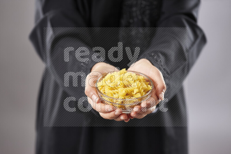 Woman in abaya holding different kinds of pasta in different positions