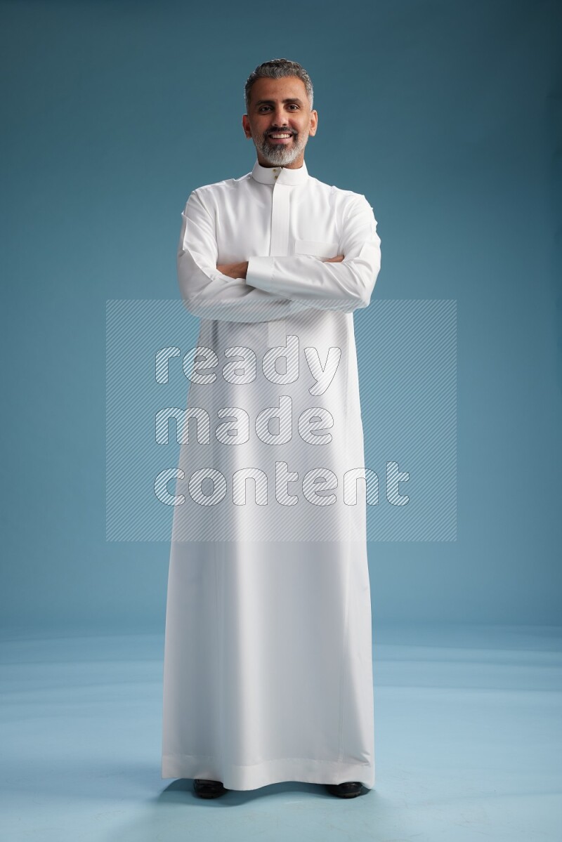 Saudi man waring thob posing to the camera on blue background