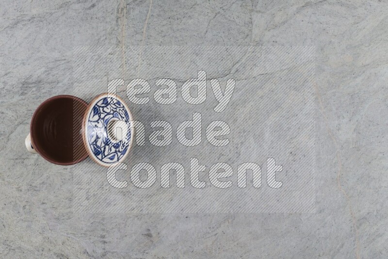 A multicolored pottery pot with its lid on grey marble background