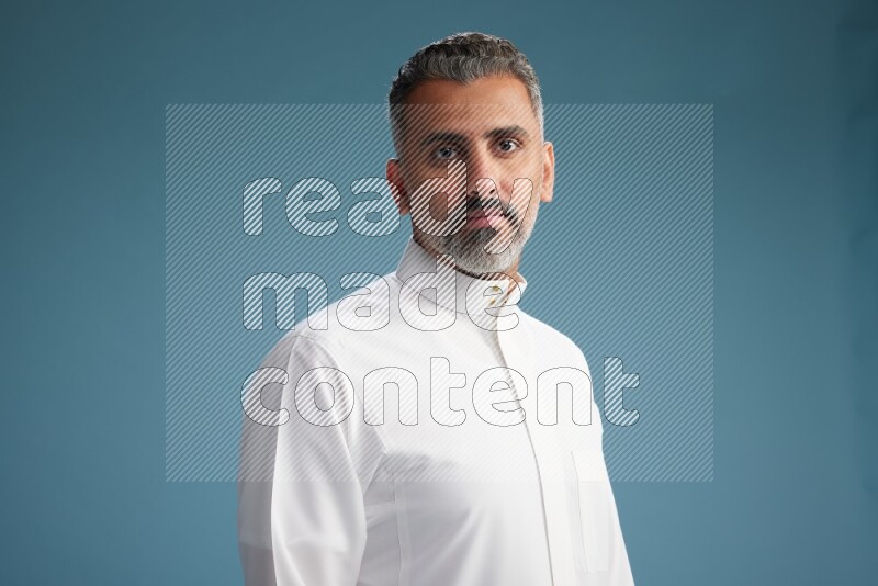 Saudi man waring thob posing to the camera on blue background