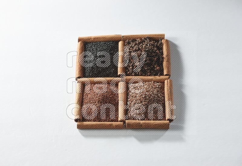4 squares of cinnamon sticks full of black seeds, cloves, flaxseeds and garden cress on white flooring