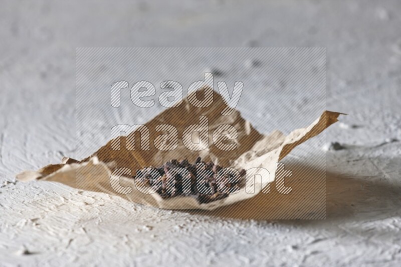 Cloves on crumpled piece of paper on a textured white flooring
