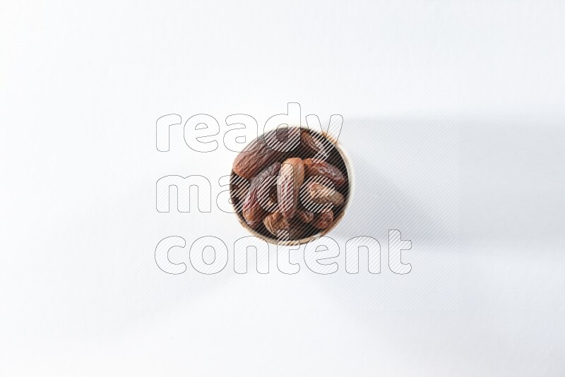 A beige ceramic bowl full of dried dates on a white background in different angles
