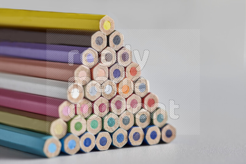 A close-up of the tips of colored pencils arranged in a bundle on white background