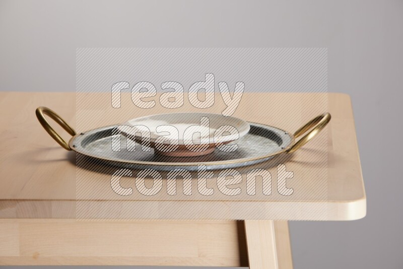 multicolored plate placed on a rounded stainless steel tray with golden handels on the edge of wooden table