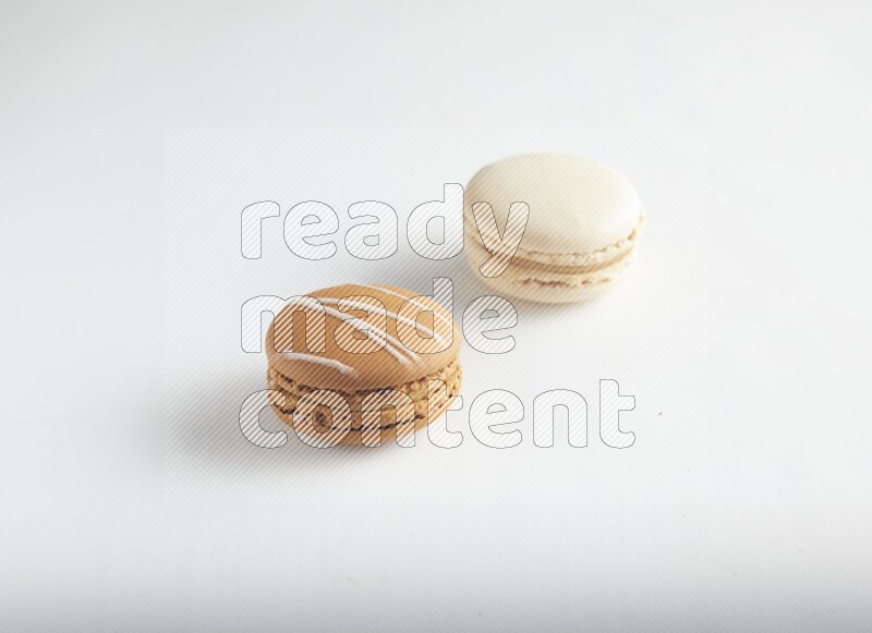 45º Shot of of two assorted Brown Irish Cream, and White Caramel fleur de sel macarons on white background