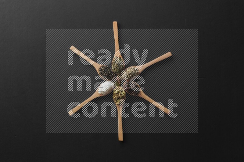 wooden spoons filled with white peppers, cloves, cardamom, salt, black peppers and basil on black flooring and shaped like a clock