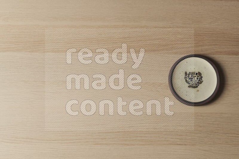A decorative pottery plate on light wooden background