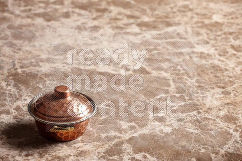 A small copper pot on beige marble background