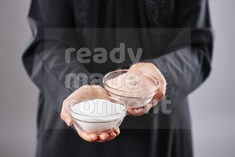 Woman in abaya holding different kinds of spices in different positions
