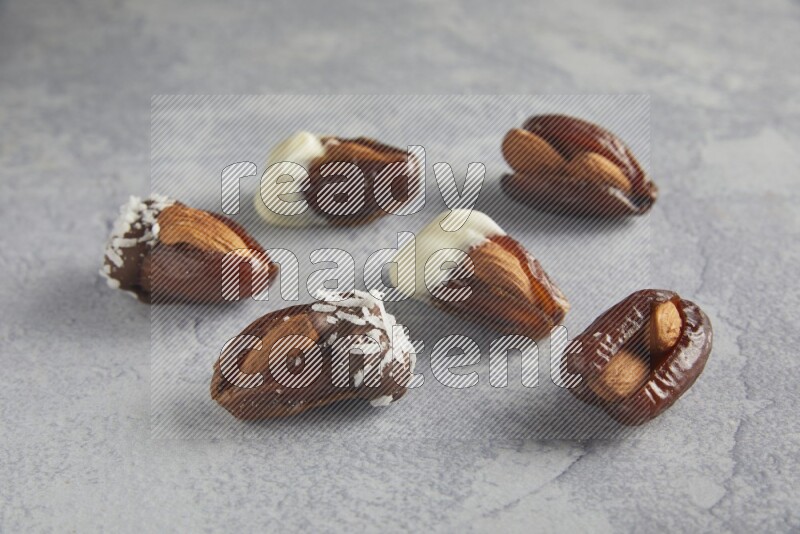 Group of Almonds stuffed dates plain and covered with chocolate on a light grey background