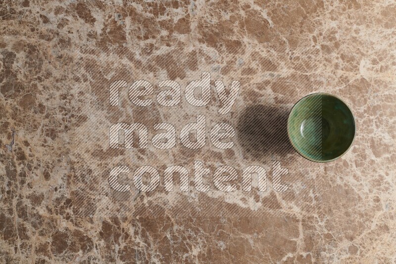 A dark green pottery bowl on beige marble background