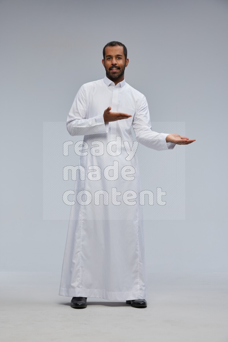Saudi man Wearing Thob standing interacting with the camera on Gray background