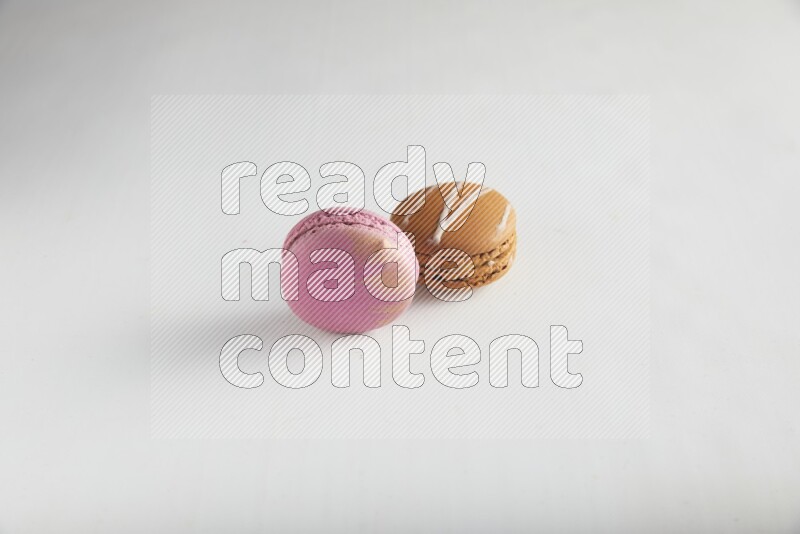 45º Shot of of two assorted Brown Irish Cream, and Purple Strawberry macarons on white background
