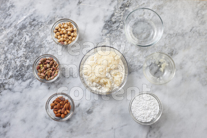 Ghoriba step by step with its ingredient, flour, powdered sugar, ghee and nuts on grey marble background